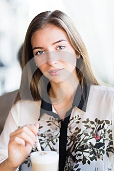 Young beautiful woman drinks coffee in restaurant