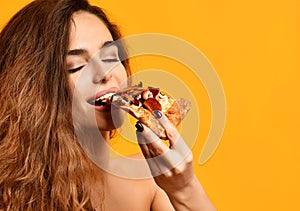 Young beautiful woman eat slice of pepperoni pizza with closed eyes smiling on yellow