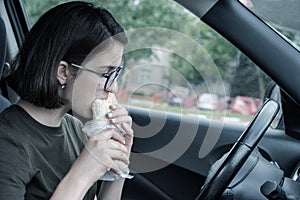 Young beautiful woman eating fast food in the car. Break. Dinner in the car. Front seat. Food concept