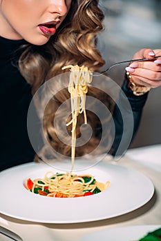 Young beautiful woman eating pasta in a restaurant.