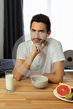 Young beautiful woman eats breakfast cereal with berries and milk