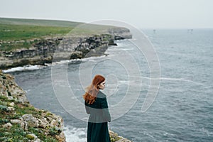 Young beautiful woman on the edge of a cliff near the sea