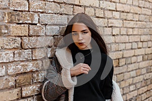 Young beautiful woman in an elegant gray checkered coat in a black fashionable t-shirt is standing