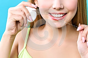 Young beautiful woman is engaged in cleaning teeth. Beautiful smile healthy white teeth. A girl holds a dental floss