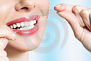 Young beautiful woman is engaged in cleaning teeth. Beautiful smile healthy white teeth. A girl holds a dental floss