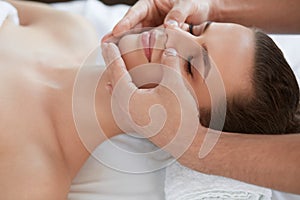 Young beautiful woman enjoying anti-aging facial massage.Male therapist making head massage to female client