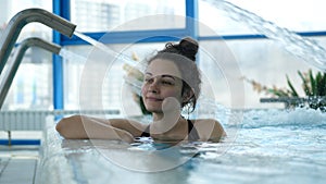 Young beautiful woman is enjoying and having relax in swimming pool in a luxury wellness center.