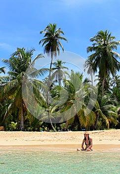Young beautiful woman enjoying her time and resting close to the sea in the southern beach of Pelicano Island, Panama.
