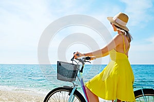 Young beautiful woman enjoying the sea view with her bicycle