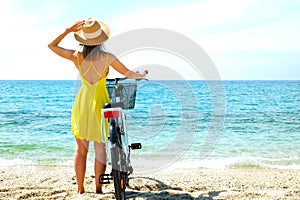 Young beautiful woman enjoying the sea view with her bicycle