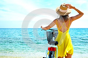 Young beautiful woman enjoying the sea view with her bicycle