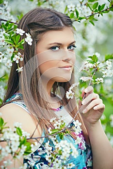 Young beautiful woman enjoying smell of blooming tree on a sunny day