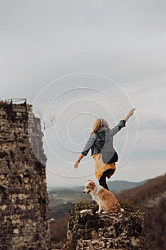 Young beautiful woman enjoying the view with her dog during hiking trip in the mountain