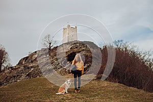 Young beautiful woman enjoying the view with her dog during hiking trip in the mountain