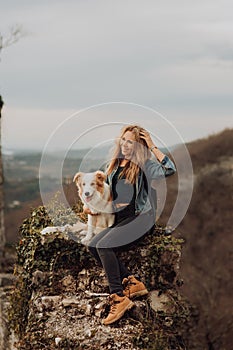 Young beautiful woman enjoying the view with her dog during hiking trip in the mountain