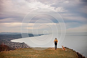 Young beautiful woman enjoying the view with her dog during hiking trip in the mountain