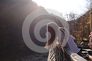 Young beautiful woman enjoys the view of the mountain river on the terrace of a cafe on a sunny autumn day. selective focus