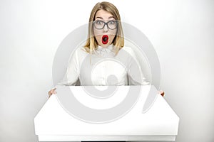Young beautiful woman in eyeglasses looking surprised recieving parcel isolated white background