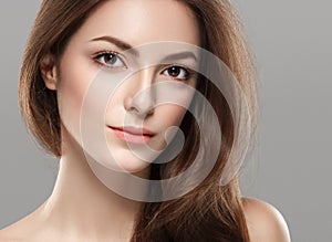 Young beautiful woman face portrait with healthy skin on gray background