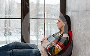 Young beautiful woman fall asleep on the windowsill while reading a book