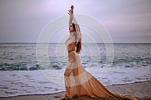 Young beautiful woman fallen angel stands on sea beach enjoy nature. costume bird white wings.