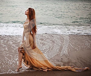 Young beautiful woman fallen angel stands on sea beach enjoy nature. costume bird white wings.