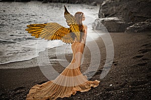 Young beautiful woman fallen angel stands on sea beach enjoy nature. costume bird white wings.