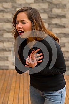 Young beautiful woman feeling bad and gripping her chest, cardiopulmonary resuscitation concept, in a blurred background