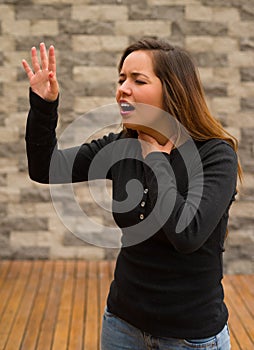 Young beautiful woman feeling bad and gripping her neck with one hand and asking for help with her other hand