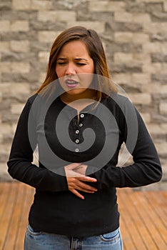 Young beautiful woman feeling bad and touching her stomach, cardiopulmonary resuscitation concept, in a blurred