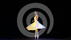 Young beautiful woman, female ballet dancer in white dress on pointe doing elements of classical ballet. Looks tender