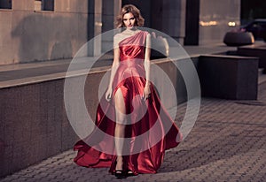 Young Beautiful Woman In Fluttering Red Dress. City Background.