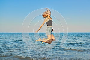 Young beautiful woman flying over the sea, happy female jumping over water