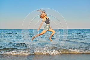 Young beautiful woman flying over the sea, happy female jumping over water