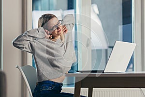 Young beautiful woman freelancer tired working at night on a laptop, completes work late