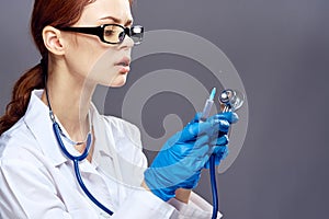 Young beautiful woman with glasses on a dark gray background holds a stethoscope, doctor, medicine