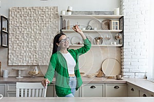 Young beautiful woman in glasses and green shirt in the kitchen having fun