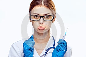 Young beautiful woman in glasses and in medical clothes holds a syringe on white isolated background, emotions, doctor, medicine