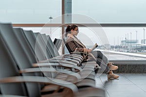 Young Beautiful Woman With Glasses Reading a Book While Waiting For Boarding at Air Jet in Airport