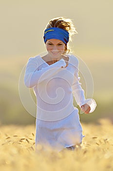 Young beautiful woman on golden cereal field in summer