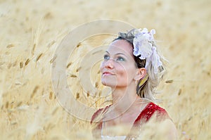 Young beautiful woman on golden cereal field in summer