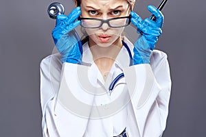 Young beautiful woman on a gray background holds medical instruments, medicine, doctor