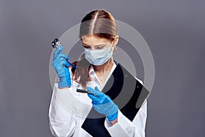 Young beautiful woman on a gray background holds medical instruments, medicine, doctor