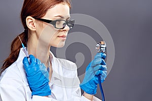 Young beautiful woman on a gray background holds in rubber gloves medical instruments, medicine, doctor