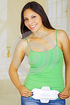 Young beautiful woman with a green blouse holding a hygenic towel, pointing in front of her body