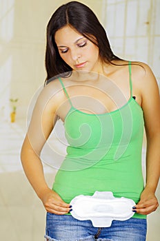 Young beautiful woman with a green blouse holding a hygenic towel, pointing in front of her body