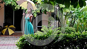 Young beautiful woman in green dress walks in the rain. Hand of women holding an umbrella.