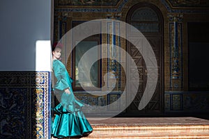 Young and beautiful woman with green frilly dress and dancing flamenco is on the stairs of plaza de espana in seville, andalusia. photo