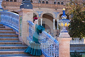 Young and beautiful woman with green frilly dress and dancing flamenco is on the stairs of plaza de espana in seville, andalusia. photo