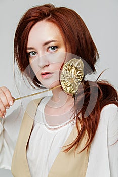 Young beautiful woman has red hair creative gold make up are posing in a studio with flowers
